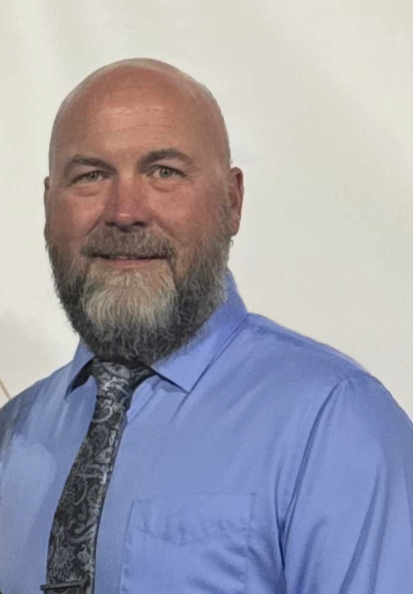 Jason fick headshot- white bald man with gray beard, smiling and wearing a blue oxford shirt
