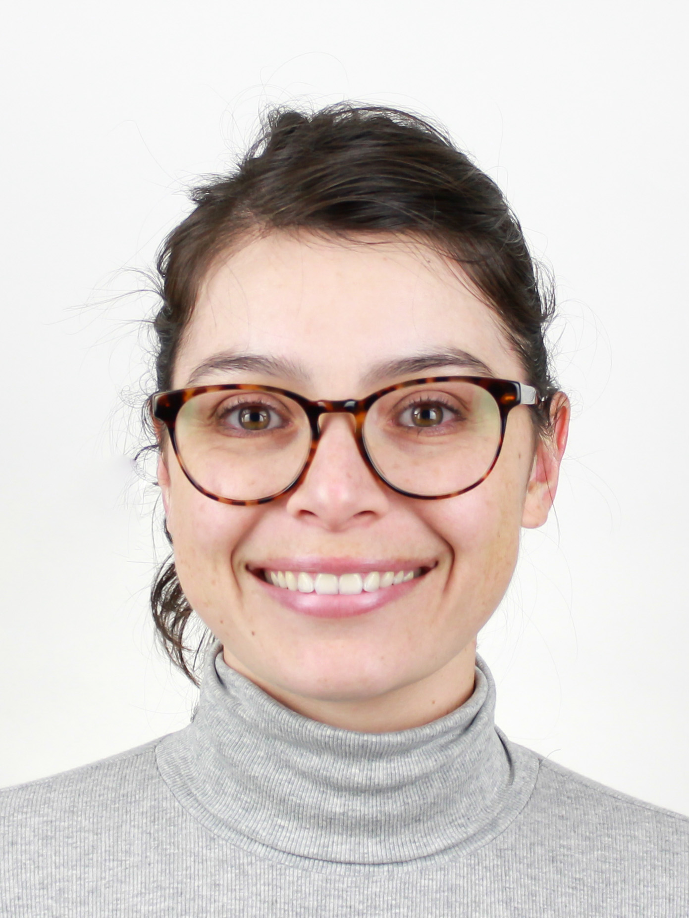 Kelsey Davis headshot, smiling woman with dark hair in a ponytail, glasses, and a gray shirt
