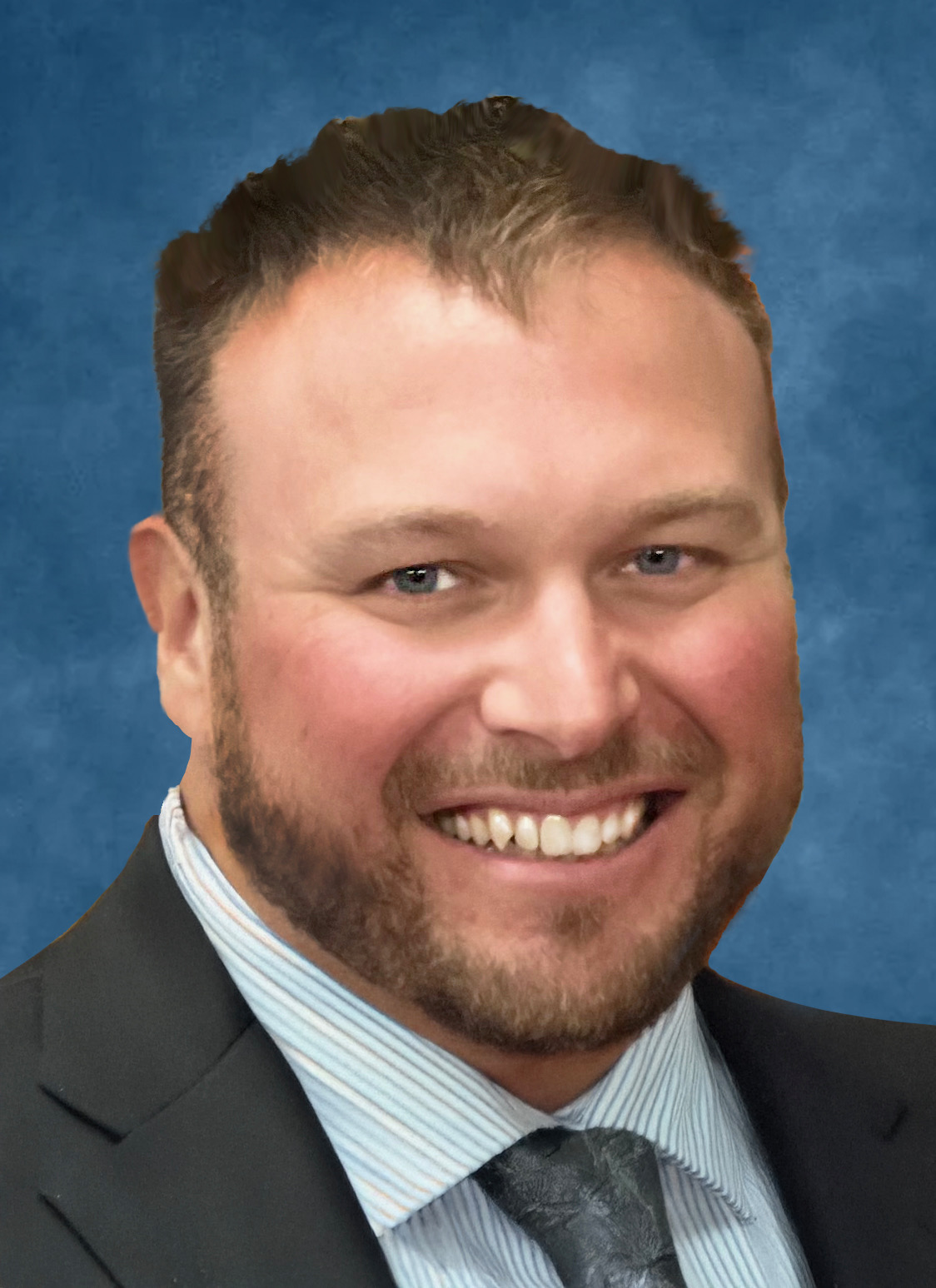 Richard Russel headshot- Smiling man in suit with short brown hair and bear